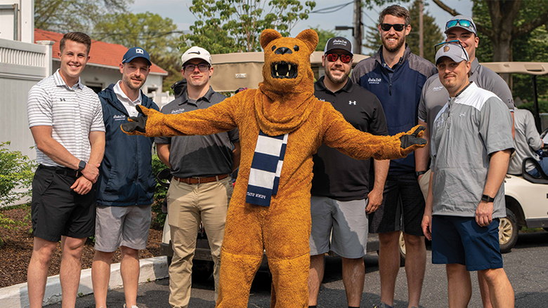Seven male golfers stand with the Nittany Lion mascot.